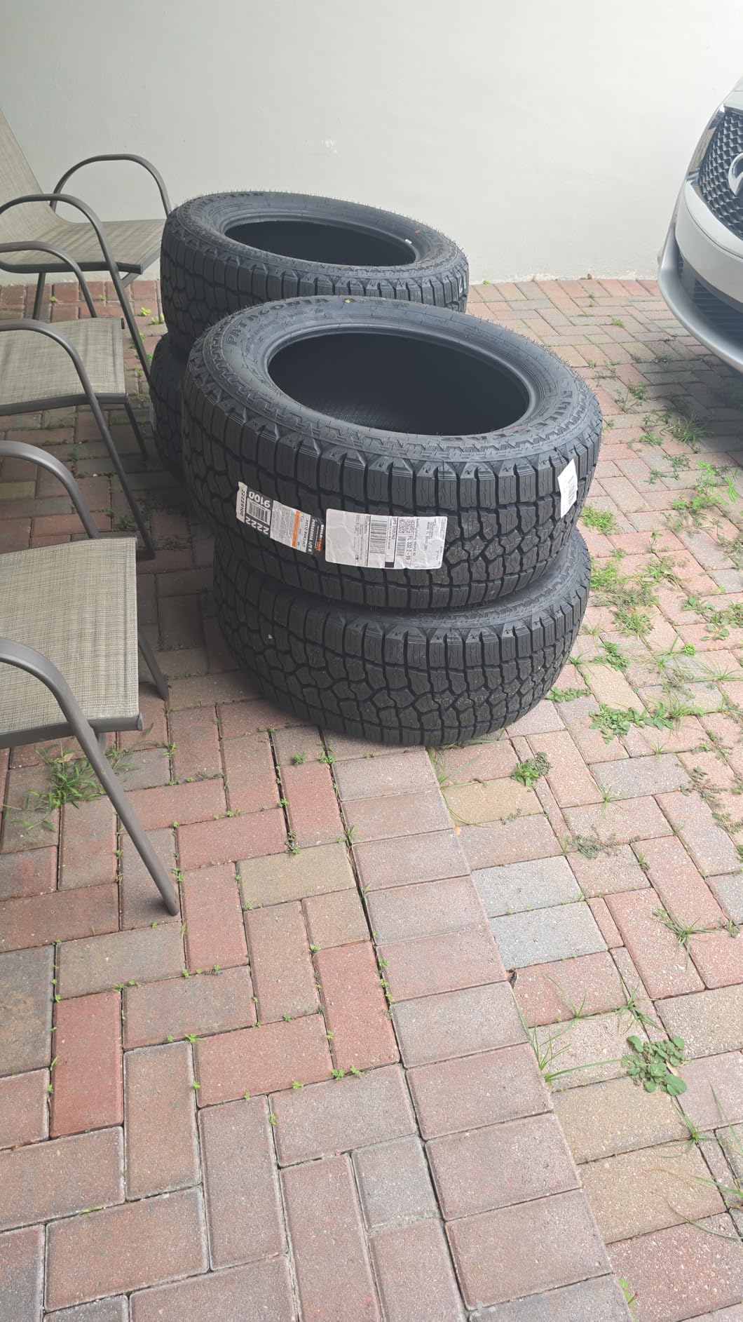 Three new Milestar Patagonia A/T tires stacked on a brick paver patio with the shipping labels still attached